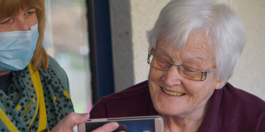 Care home worker holds phone up to resident - care home closure