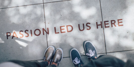 Two pairs of feet on floor with 'passion led us here' written on it - GPs South East England