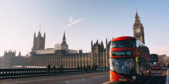 Double decker bus crossing London Bridge with Big Ben and Parliament in the background