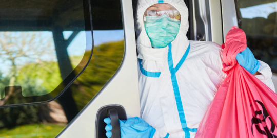 Man with mask and safety suit with hazardous waste bag