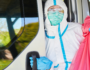 Man with mask and safety suit with hazardous waste bag